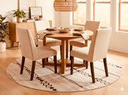 6' round beige and cream geometric washable area rug placed under a round dining table with upholstered chairs in a warm modern dining space.