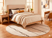 6' round beige and cream geometric washable area rug styled beneath a bed in a bright bedroom with neutral bedding and warm wood furniture.