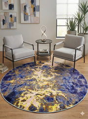 6' round navy blue and gold abstract rug placed between two accent chairs with a modern side table in a contemporary sitting area.