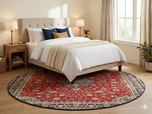 6' round red blue cream traditional floral medallion area rug styled beneath a bed in a bright, neutral bedroom.