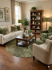 6' round soft olive green and cream textured abstract area rug placed beneath a coffee table in a cozy living room with green accents.