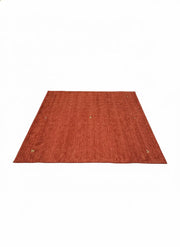 6' x 6' square rust burnt orange solid modern washable area rug featuring subtle textured tones with a non-slip backing.