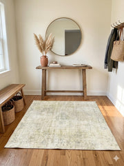 6' x 6' square soft sage and light cream distressed area rug placed in a bright entryway beneath a wooden console table and round mirror.