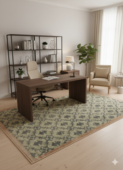 6' x 9' Rectangle Sage Green & Charcoal Medallion Traditional Washable Area Rug placed in a modern home office with a wooden desk, cream chair, black shelving unit, and indoor plants.