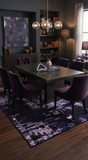 6' x 9' Rectangular Black Purple Distressed Abstract Modern Washable Area Rug styled in a dining room with a black dining table and purple upholstered chairs.