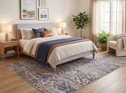 6' x 9' Rectangular Blue Beige Distressed Geometric Tribal Southwestern Area Rug placed in a cozy bedroom with a wooden bed, white bedding, blue and rust accent pillows, and a cream upholstered chair.