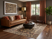 6' x 9' Rectangular Brown Beige Floral Traditional Washable Area Rug styled in a living room with a brown leather sofa, wooden accent chairs, and a round dark coffee table.