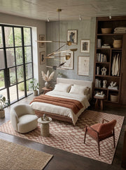 6' x 9' Rectangular Brown Ivory Checkered Geometric Modern Washable Area Rug styled in a bedroom with a beige bed, white accent chair, and wooden bookshelf.