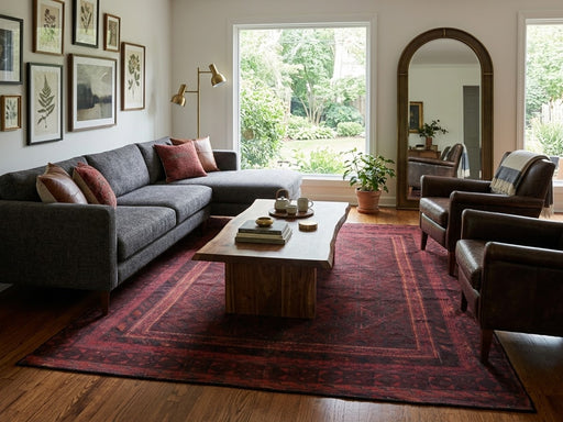 6' x 9' Rectangular Burgundy Black Distressed Geometric Tribal Traditional Area Rug styled in a living room with a gray sectional sofa and wooden coffee table.