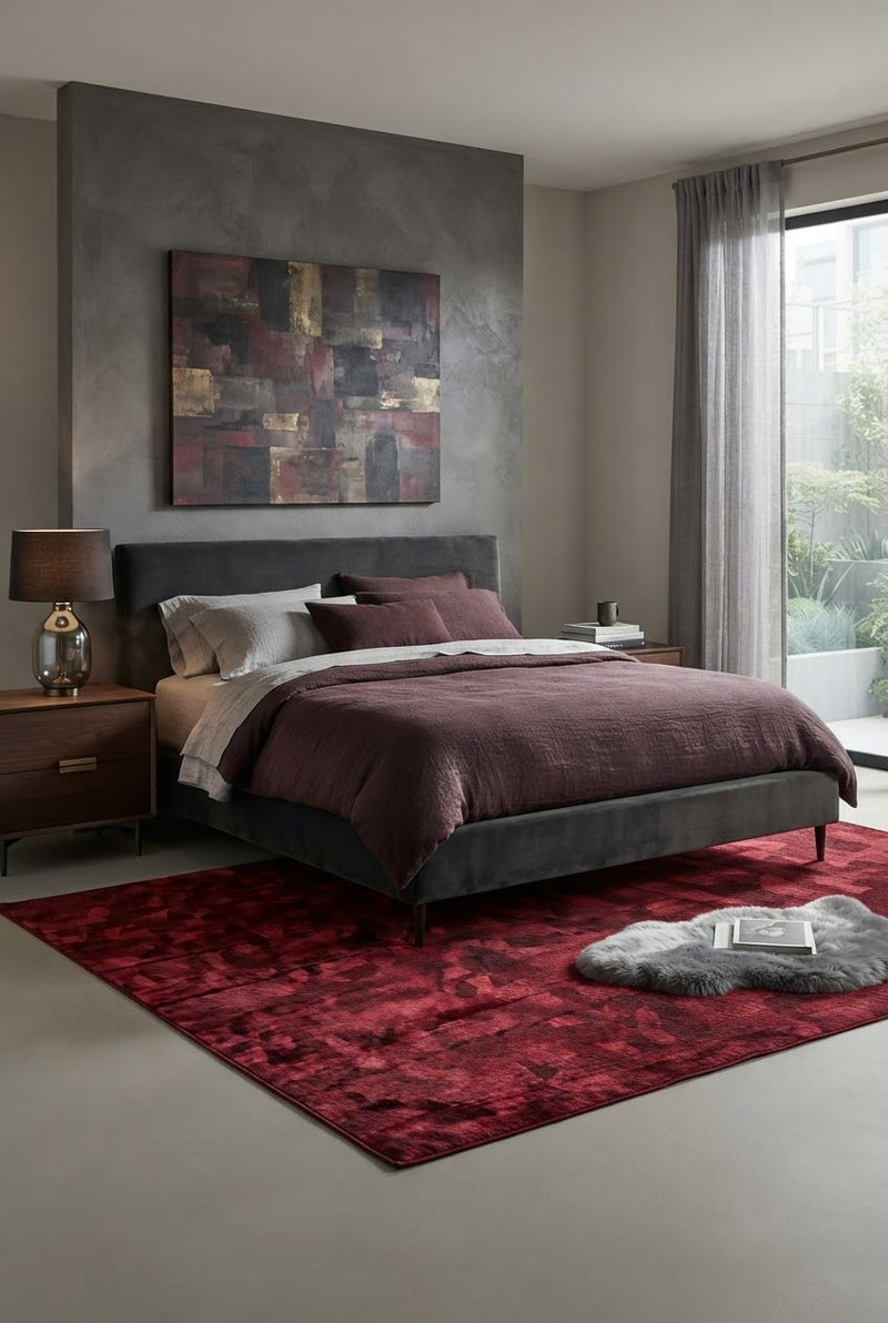 6' x 9' Rectangular Burgundy Red Abstract Geometric Modern Area Rug styled in a bedroom with a dark gray upholstered bed and burgundy bedding.
