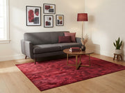 6' x 9' Rectangular Burgundy Red Abstract Geometric Modern Area Rug styled in a living room with a gray sofa and round wooden coffee table.