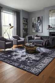 6' x 9' Rectangular Charcoal Gray Distressed Floral Medallion Traditional Washable Area Rug styled in a living room with a gray sofa and round glass coffee table.