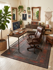 6' x 9' Rectangular Dark Brown & Rust Tribal Border Traditional Washable Area Rug styled in a home office with a desk, chair, and indoor plants.