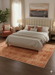 6' x 9' burnt orange and soft brown textured modern area rug placed partially under a bed in a cozy neutral bedroom.