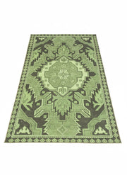 6' x 9' geometric washable area rug featuring layered sage and olive green tones with a bold tribal-inspired central medallion pattern.
