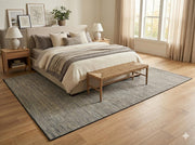 6' x 9' gray and beige solid modern washable area rug styled beneath a bed in a calm bedroom with neutral bedding, wood nightstands, and soft natural light.