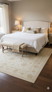 6' x 9' ivory and beige floral traditional rectangular area rug placed partially under a bed in a soft neutral bedroom.
