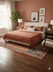 6' x 9' multi-color southwestern geometric rectangular area rug placed partially under a bed in a warm bedroom with terracotta accents and neutral decor.