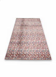 6' x 9' rectangular area rug featuring a rose pink background with teal and ivory geometric transitional patterns.