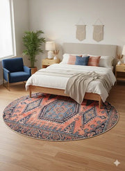 7' Round Orange & Navy Blue Tribal Traditional Area Rug placed / styled in a bright bedroom centered under a wooden bed with neutral bedding and blue accent chair.