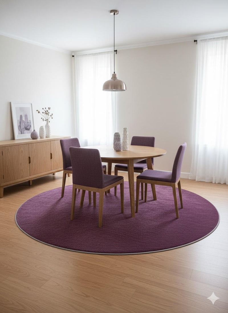 7' Round Purple Deep Violet Undertones Solid Modern Area Rug placed / styled in a contemporary dining room under a round wooden table with four upholstered chairs.