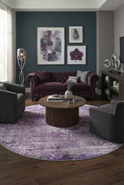 7' Round Purple Lavender Gray Distressed Abstract Modern Area Rug styled in a living room with a purple velvet sofa and round wooden coffee table.