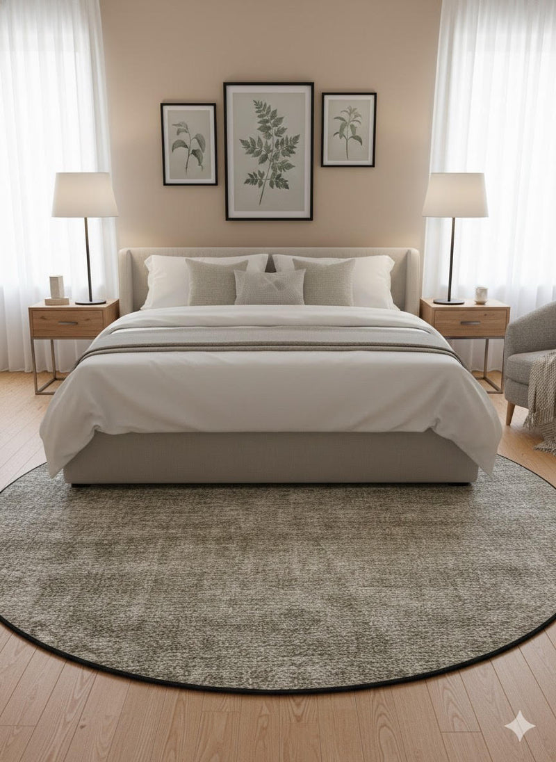 7' round beige, ivory, taupe, and gray heathered washable area rug placed beneath a modern bed in a calm, minimalist bedroom with neutral furnishings.