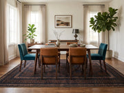 7' x 10' Rectangular Black Rust Brown Distressed Geometric Tribal Traditional Area Rug placed in a dining room with a wooden dining table and upholstered chairs.