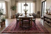 7' x 10' Rectangular Burgundy & Black Geometric Tribal Southwestern Area Rug styled in a dining room beneath a wooden dining table and dark wooden chairs.