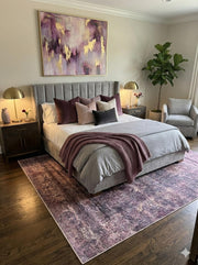 7' x 10' Rectangular Purple & Subtle Gray Distressed Modern Area Rug placed in a neutral bedroom under a gray upholstered bed.