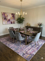 7' x 10' Rectangular Purple & Subtle Gray Distressed Modern Area Rug styled in a modern dining room beneath a dark wood table and gray chairs.