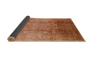 7' x 10' Rectangular Rust Mango Orange & Beige Floral Medallion Oriental Mid-Century Modern Area Rug partially rolled showing backing on a white background.