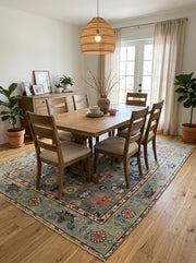 7' x 10' Rectangular Sage Green Multicolor Floral Tribal Traditional Washable Area Rug styled in a dining room with a wooden dining table, matching chairs, and woven pendant light.