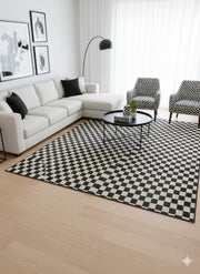 7' x 10' black and ivory off-white checkered geometric modern rectangular area rug placed under a round coffee table in a contemporary living room with neutral seating and bold monochrome accents.