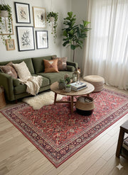7' x 10' red, beige, and soft brown floral medallion traditional area rug placed under a round coffee table in a cozy living room with a green sofa and natural decor accents.
