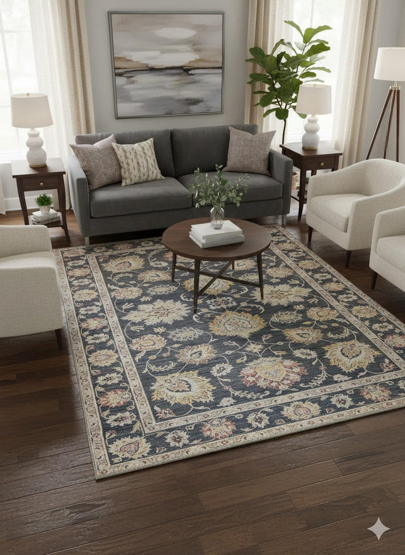 7' x 7' square charcoal and gold floral traditional area rug placed in a living room with a gray sofa, cream accent chairs, and dark wood flooring.