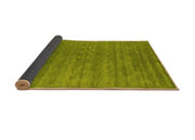 7' x 9' Abstract Green Olive Contemporary Area Rug rolled corner view highlighting the flexible backing and neatly finished edges.
