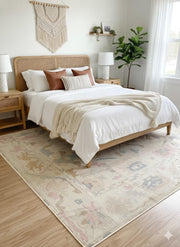 7' x 9' Ivory Pastel Multi Color Tribal Medallion Area Rug placed / styled in a bright neutral bedroom under a light wood bed frame with white bedding, woven nightstands, and soft natural décor.