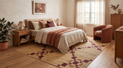 7' x 9' Rectangular Beige Burgundy Diamond Geometric Modern Area Rug styled in a bedroom with a wooden bed frame and rust-colored accent chair.