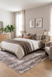 7' x 9' Rectangular Beige Gray Distressed Abstract Modern Area Rug placed in a bedroom with a beige upholstered bed, white bedding, and wooden nightstands.