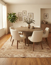 7' x 9' Rectangular Beige Rust Distressed Floral Vintage Traditional Washable Area Rug styled in a dining room with a round wooden table and cream upholstered chairs.