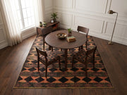 7' x 9' Rectangular Black Rust Diamond Geometric Southwestern Area Rug styled in a dining room with a round wooden dining table and wooden chairs.