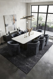 7' x 9' Rectangular Charcoal Gray Ivory Distressed Diamond Geometric Modern Washable Area Rug styled in a dining room with a white dining table and dark gray upholstered chairs.