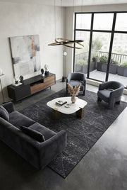 7' x 9' Rectangular Charcoal Gray Ivory Distressed Diamond Geometric Modern Washable Area Rug styled in a living room with a dark gray sofa and white coffee table.