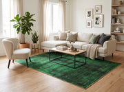 7' x 9' Rectangular Emerald Green & Black Distressed Abstract Modern Washable Area Rug styled in a living room with a cream sectional sofa and wooden coffee table.
