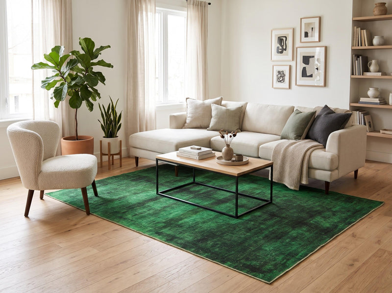 7' x 9' Rectangular Emerald Green & Black Distressed Abstract Modern Washable Area Rug styled in a living room with a cream sectional sofa and wooden coffee table.
