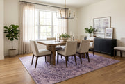 7' x 9' Rectangular Lavender Purple Distressed Floral Medallion Vintage Traditional Area Rug styled in a dining room with a wooden dining table and cream upholstered chairs.