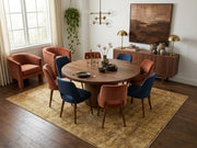7' x 9' Rectangular Mustard Gold Beige Distressed Floral Vintage Traditional Area Rug styled in a dining room with a round wooden dining table and blue and rust upholstered chairs.