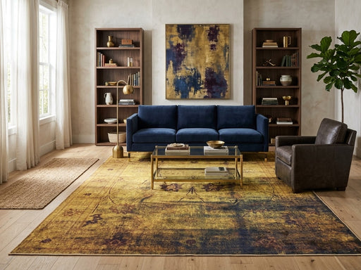 7' x 9' Rectangular Mustard Gold Charcoal Gray Distressed Floral Vintage Traditional Area Rug styled in a living room with a navy blue sofa and glass coffee table.