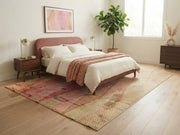 7' x 9' Rectangular Pink Beige Wavy Geometric Abstract Modern Area Rug placed in a bedroom with a pink upholstered bed, white bedding, and wooden nightstands.